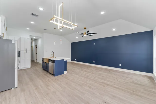 a large room with stainless steel appliances a large kitchen island a refrigerator and a dresser