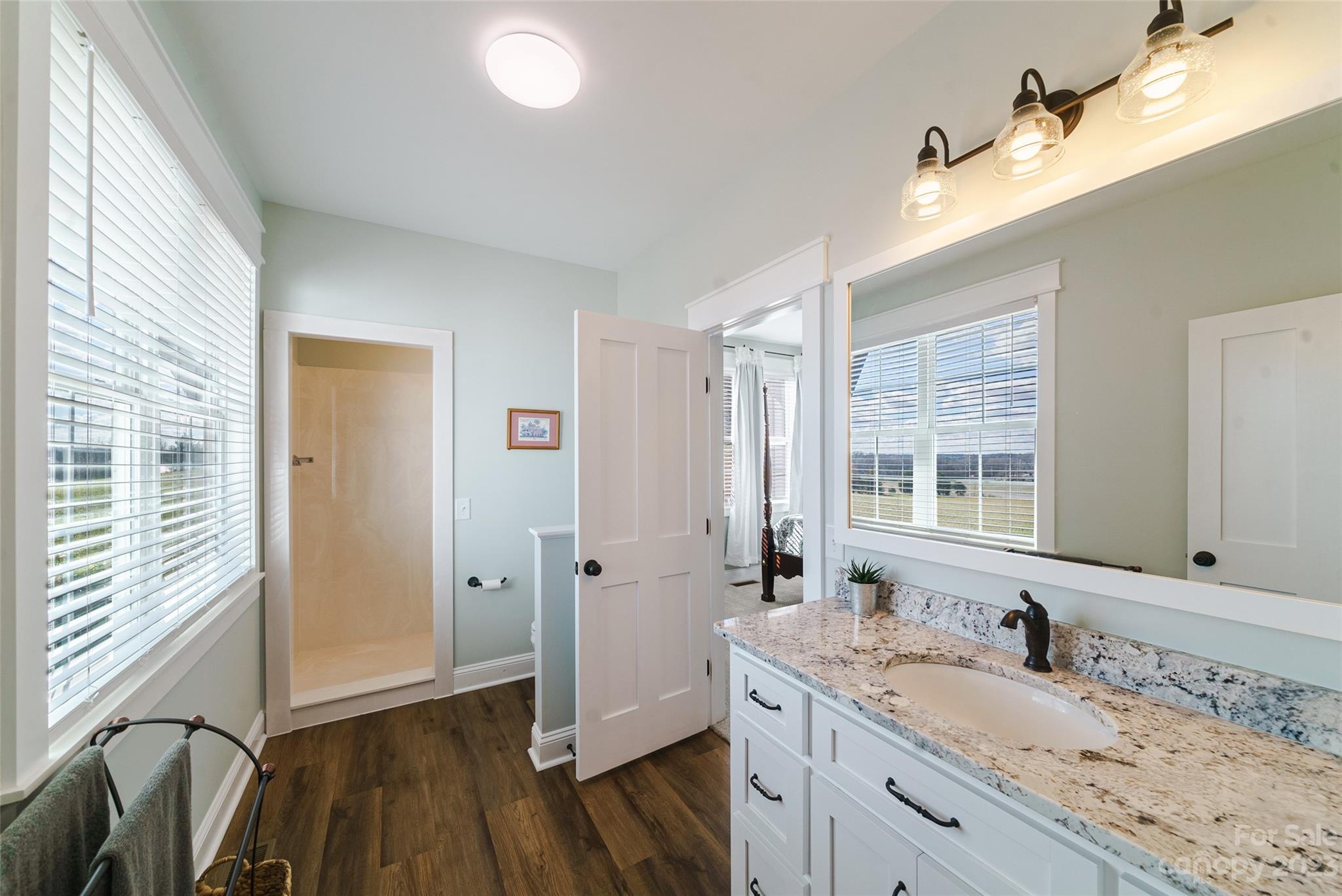 16063 McLester Road Oakboro, NC 28129 - Photo 27 of 48 a bathroom with a granite countertop sink a mirror and a shower