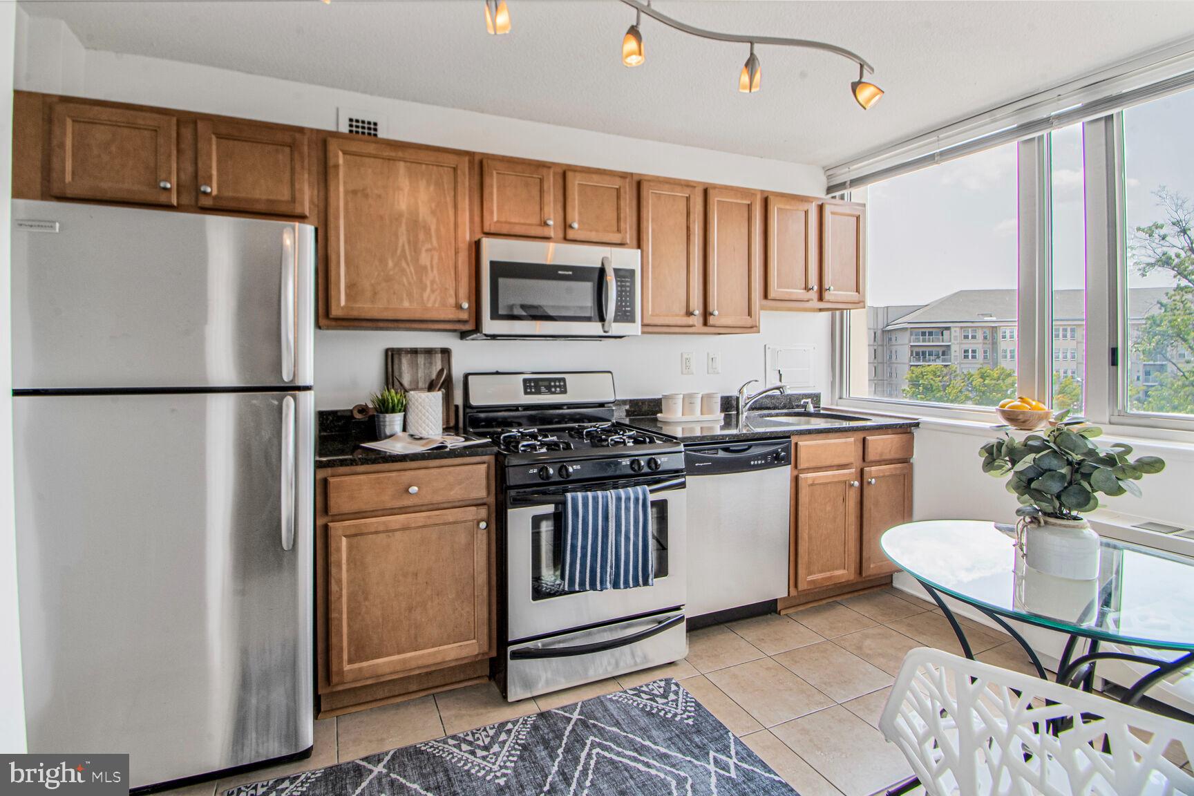 1220 Blair Mill Road, Unit 605 Silver Spring, MD 20910 - Photo 18 of 46 a kitchen with stainless steel appliances granite countertop a refrigerator a stove a sink a dining table and chairs
