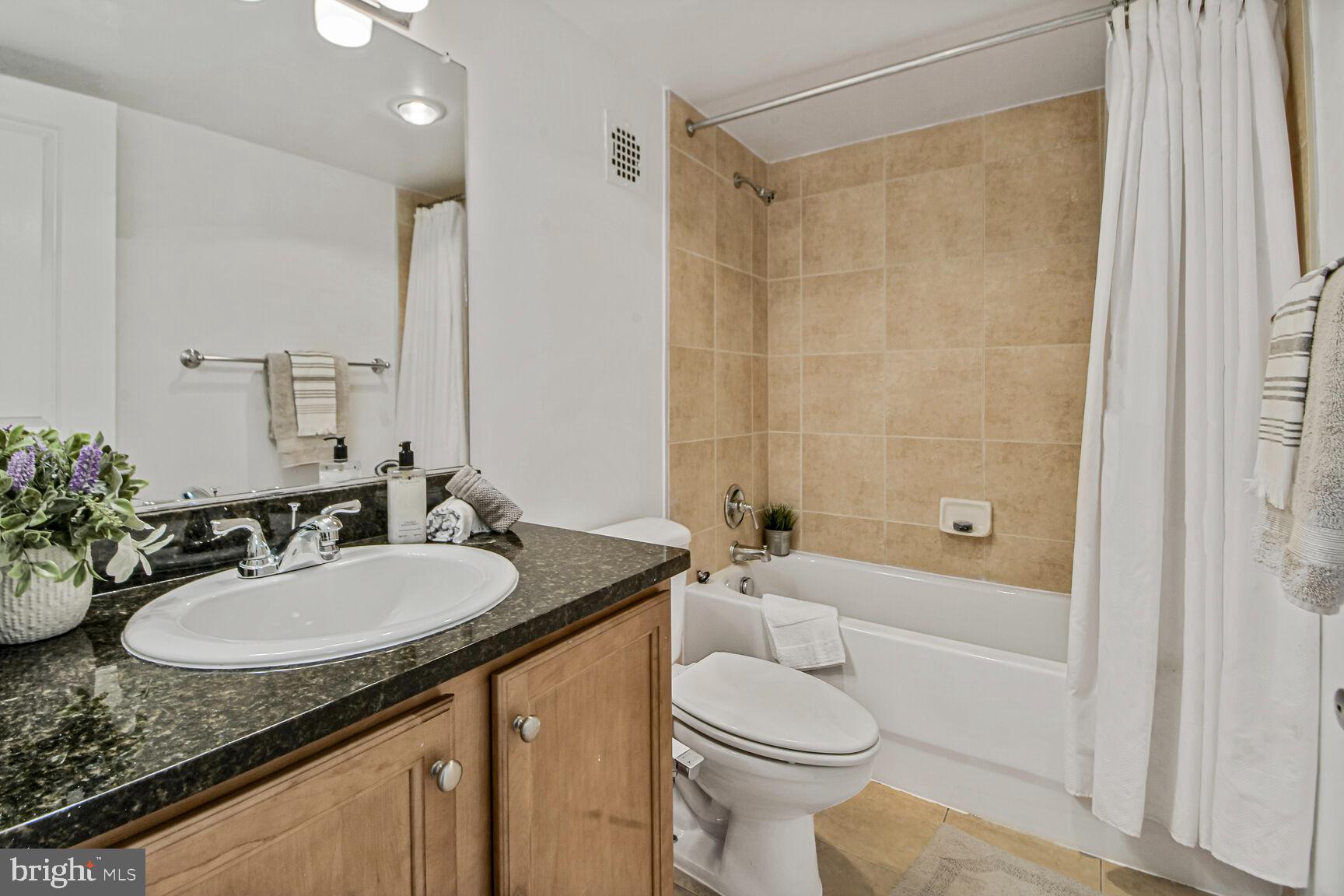 1220 Blair Mill Road, Unit 605 Silver Spring, MD 20910 - Photo 28 of 46 a bathroom with a granite countertop sink toilet a shower and a mirror
