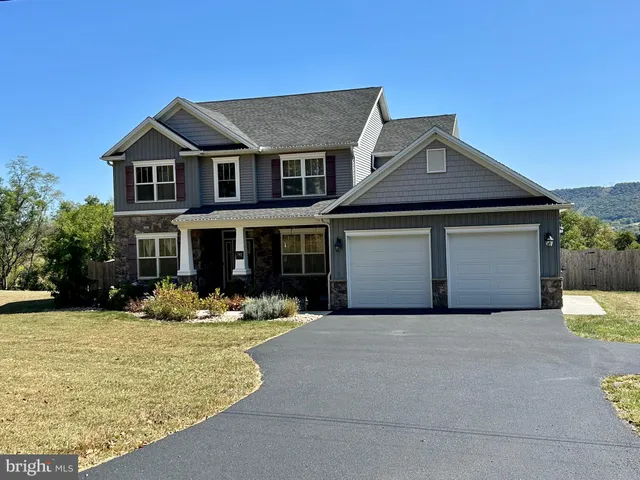 a front view of a house with yard and trees in the background