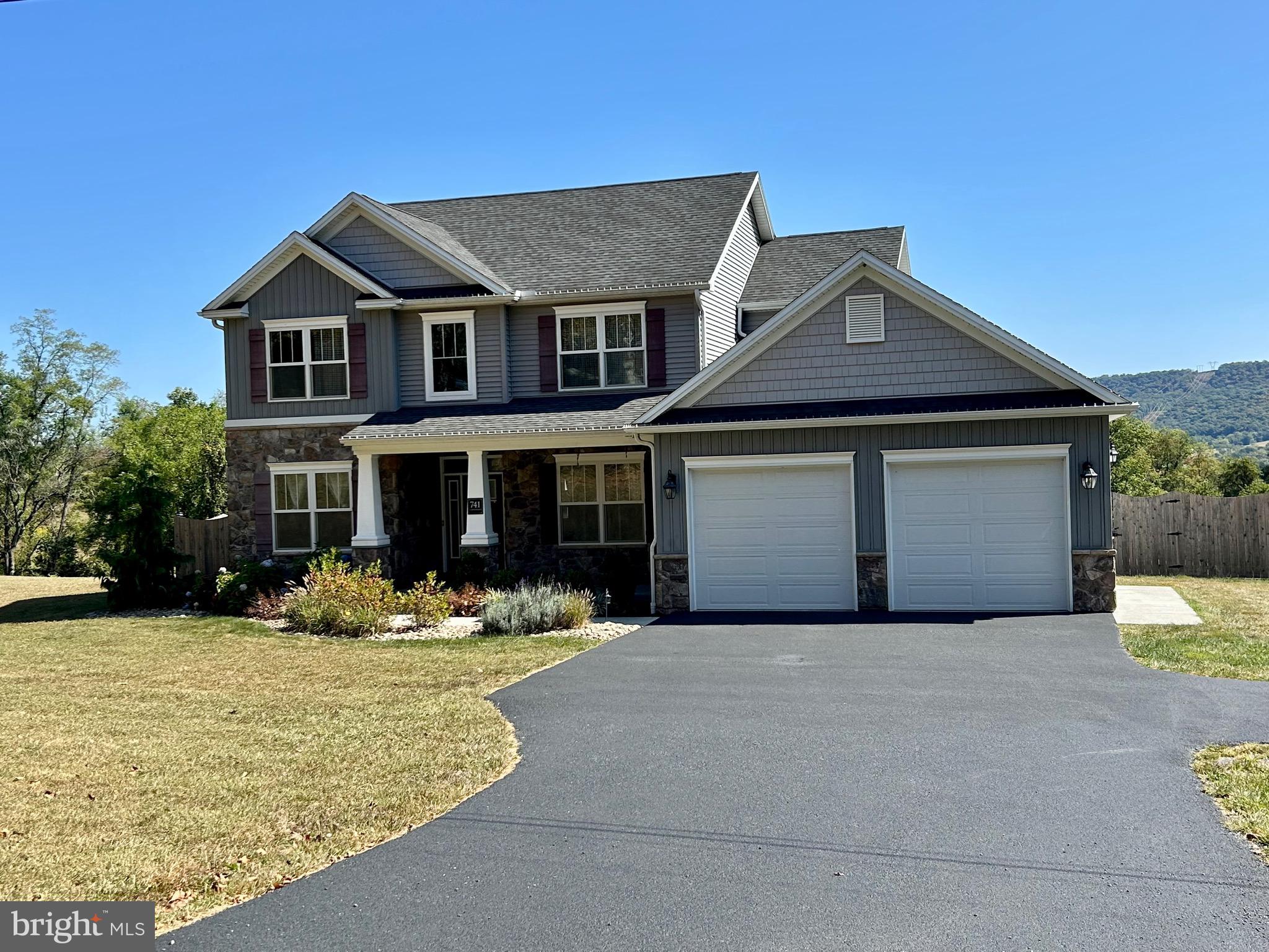 a front view of a house with yard and trees in the background