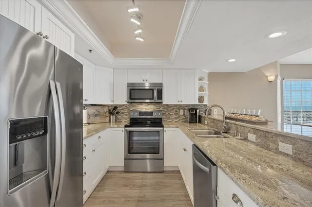 a kitchen with stainless steel appliances granite countertop a refrigerator and a stove top oven