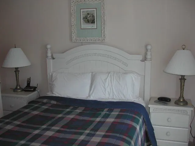 a bedroom with a bed and a lamp on the dresser