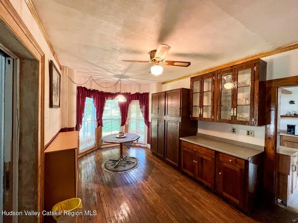 a living room with stainless steel appliances granite countertop a refrigerator a sink dishwasher a dining table and chairs with wooden floor