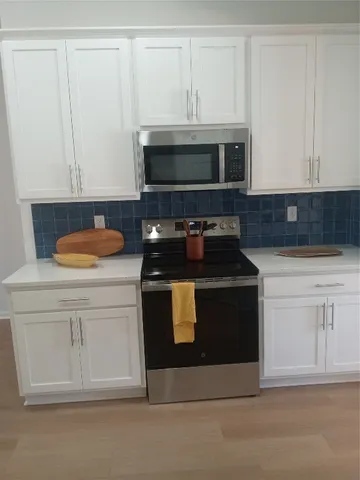 a kitchen with white cabinets and black appliances