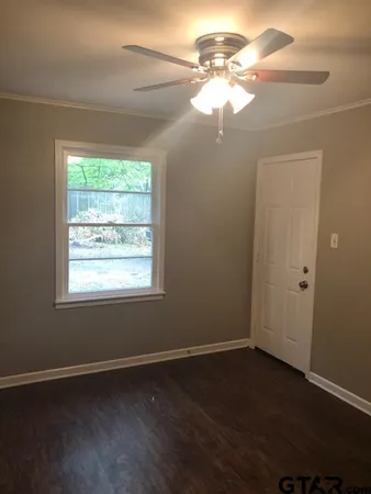 an empty room with wooden floor and fan
