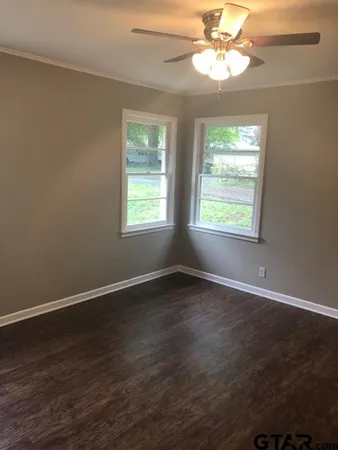 an empty room with wooden floor chandelier fan and windows