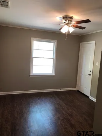 a view of an empty room with wooden floor and a window
