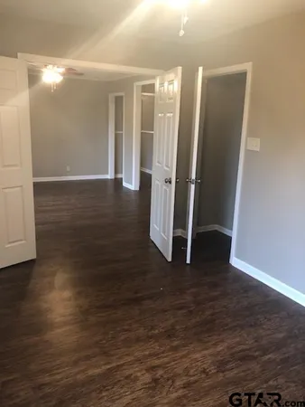 an empty room with wooden floor chandelier fan and windows