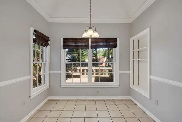 a view of an empty room with window and chandelier fan