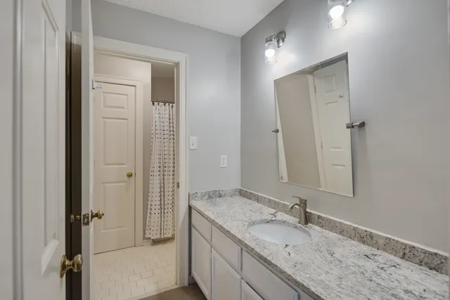 a bathroom with a granite countertop sink mirror and a shower