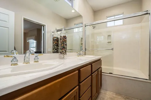 a bathroom with a double vanity sink mirror and shower