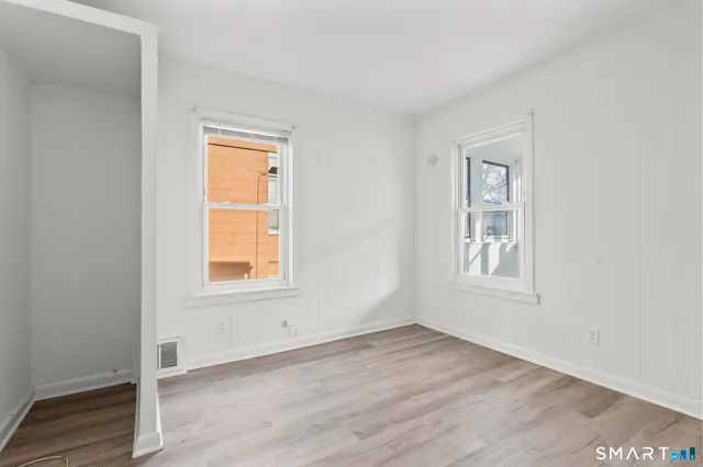 an empty room with wooden floor and windows