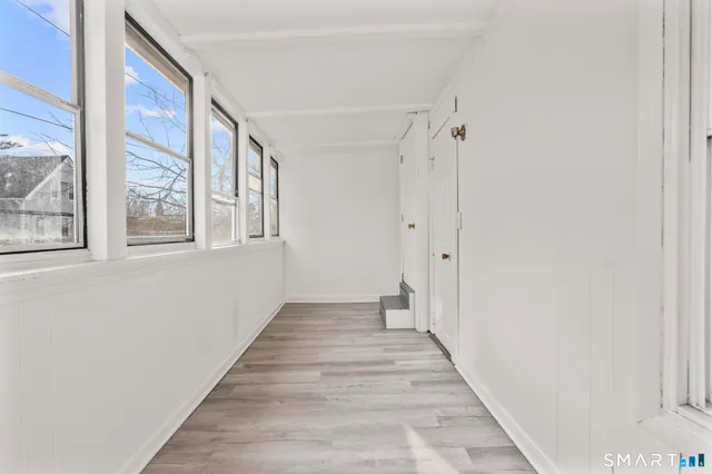 a view of a hallway with wooden floor and windows