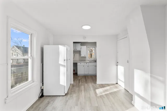 a view of a kitchen with refrigerator and wooden floor