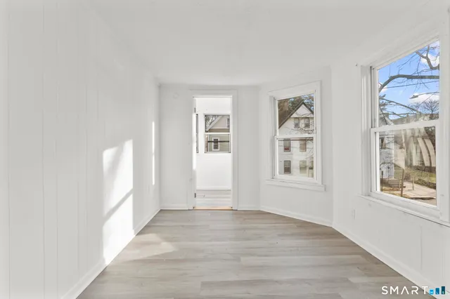a view of an empty room with a window and wooden floor