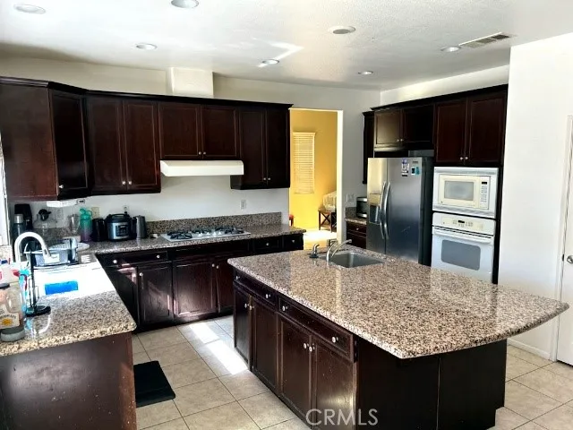 a kitchen with stainless steel appliances granite countertop a sink refrigerator and cabinets
