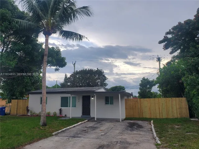 a view of a white house next to a yard with palm trees