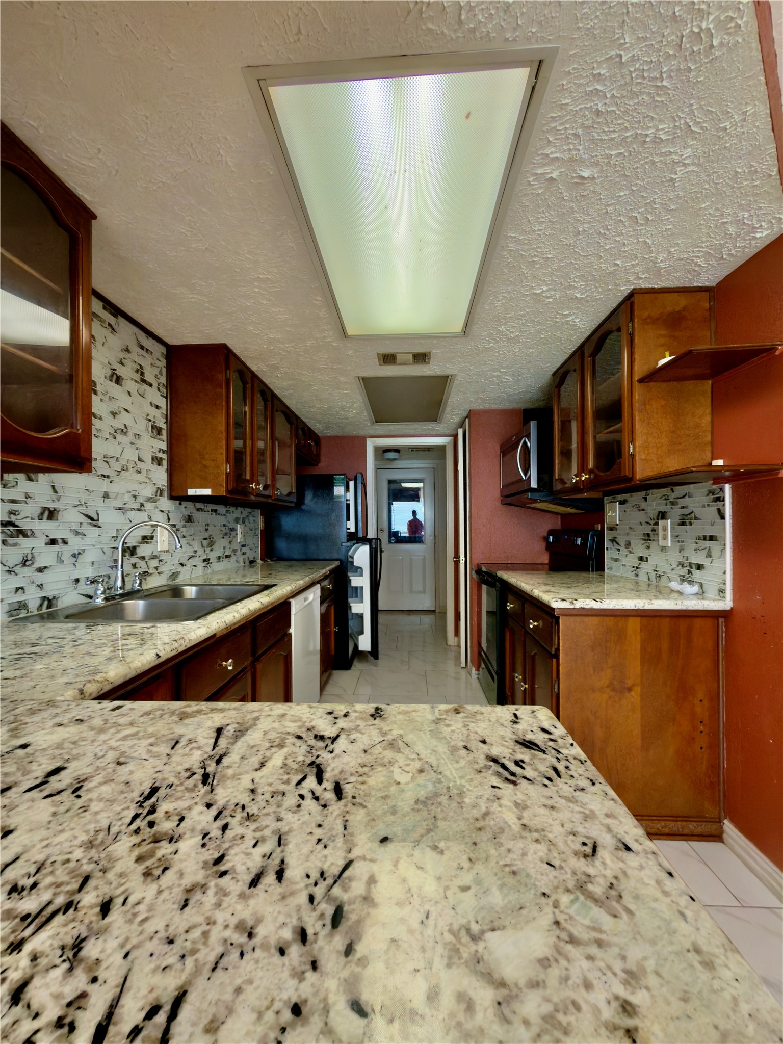 23115 Bright Star Road Spring, TX 77373 - Photo 5 of 14 a kitchen with stainless steel appliances kitchen island granite countertop a stove a sink and a microwave