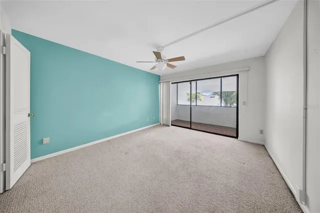 an empty room with windows and ceiling fan