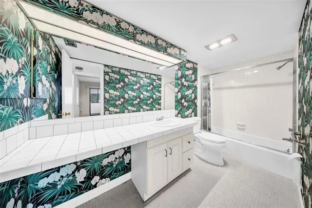 a bath room with a toilet a sink and a large mirror