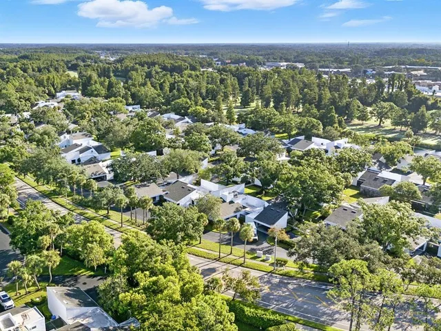 an aerial view of residential houses with outdoor space and trees