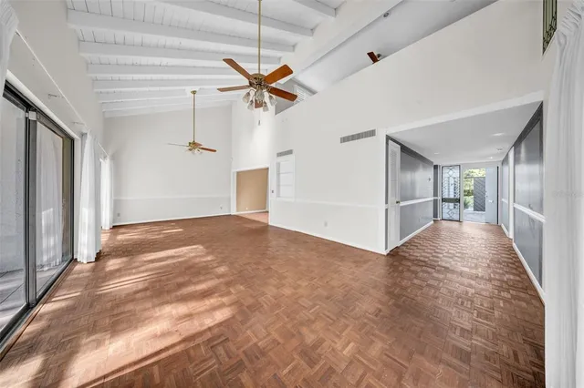 a view of empty room with wooden floor and fan