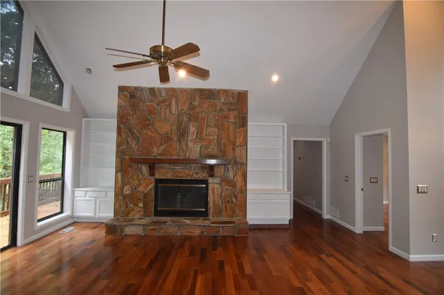 a view of an empty room with wooden floor fireplace and a window
