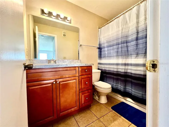 a bathroom with a granite countertop toilet sink and mirror