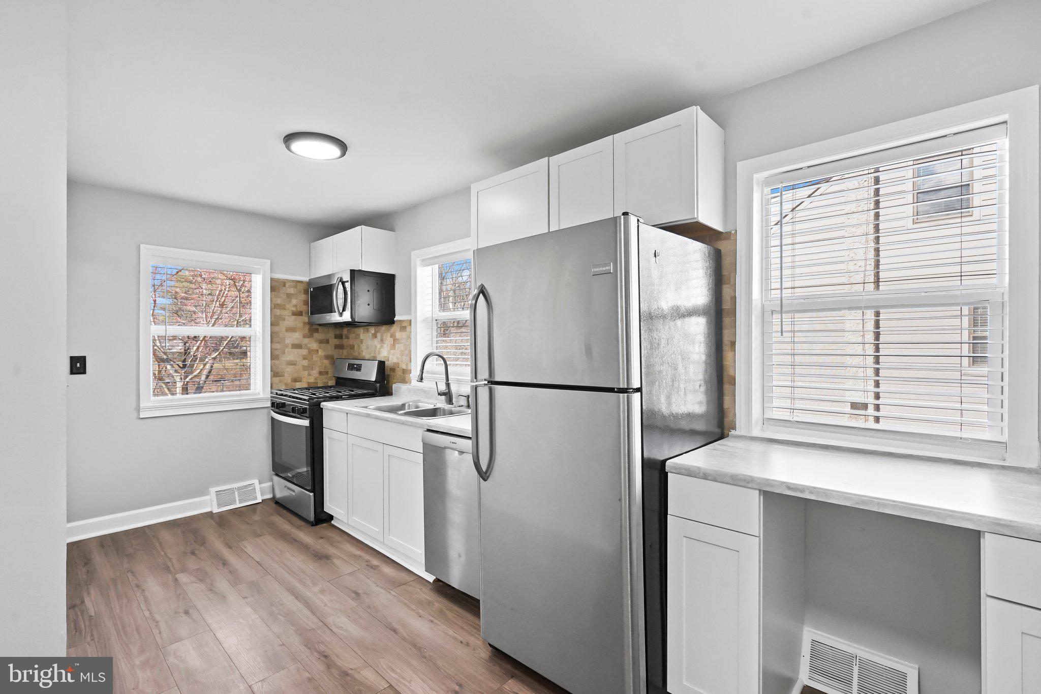 312 Wynnewood Road Ewing, NJ 08628 - Photo 4 of 24 a kitchen with a refrigerator a stove top oven a sink and a window