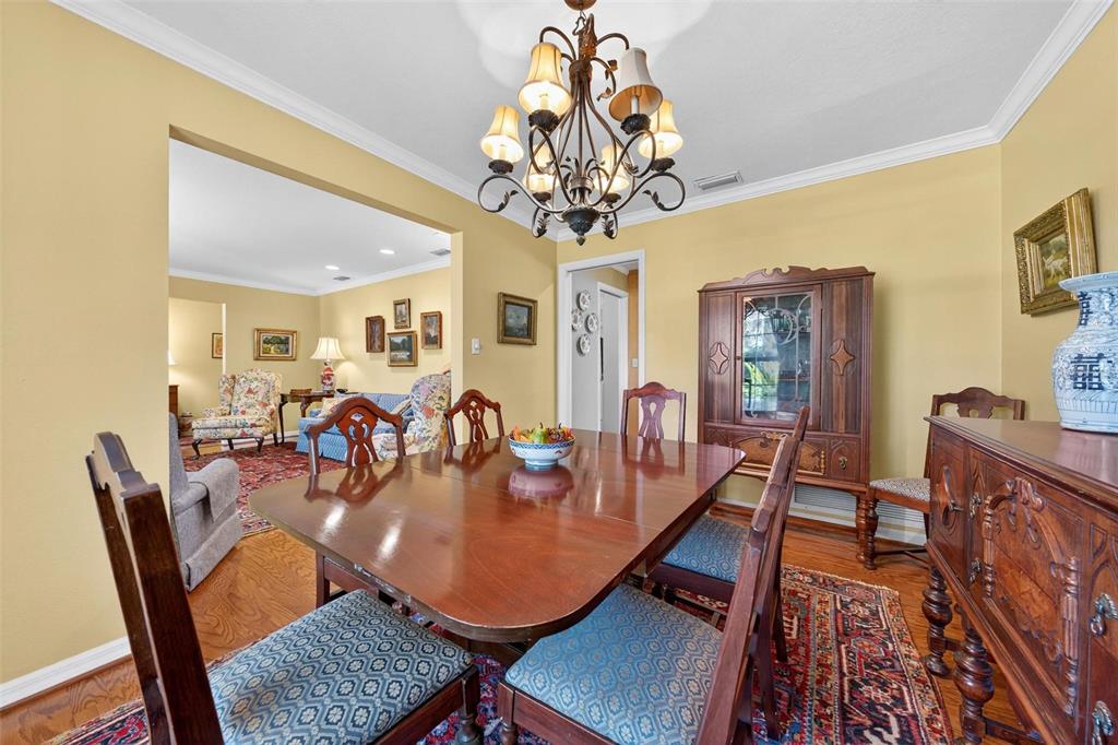 1053 Sweetbriar Road Orlando, FL 32806 - Photo 30 of 79 a dining room with wooden floor a chandelier a wooden table and chairs