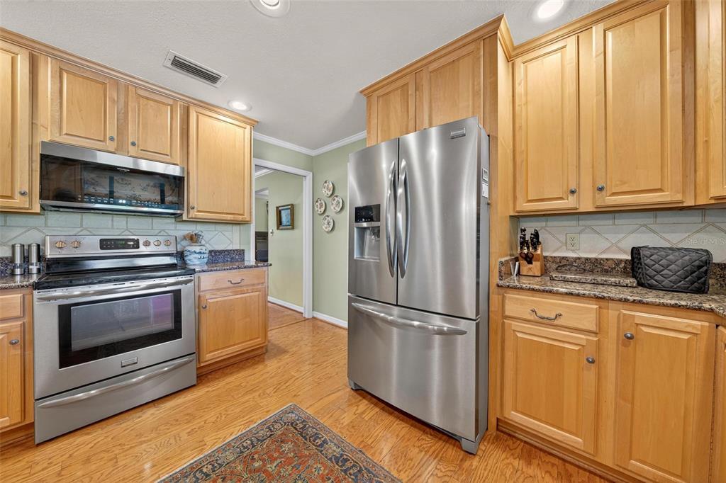 1053 Sweetbriar Road Orlando, FL 32806 - Photo 38 of 79 a kitchen with granite countertop a refrigerator stove and microwave