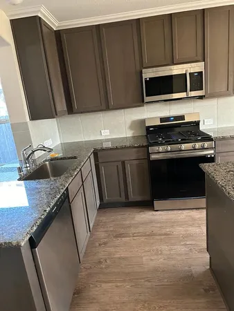 a kitchen with stainless steel appliances granite countertop a stove top oven microwave and cabinets