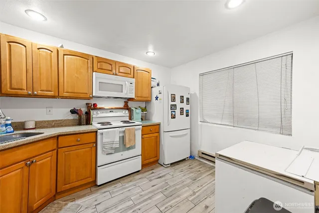 a kitchen with stainless steel appliances granite countertop a stove a sink and white cabinets with wooden floors