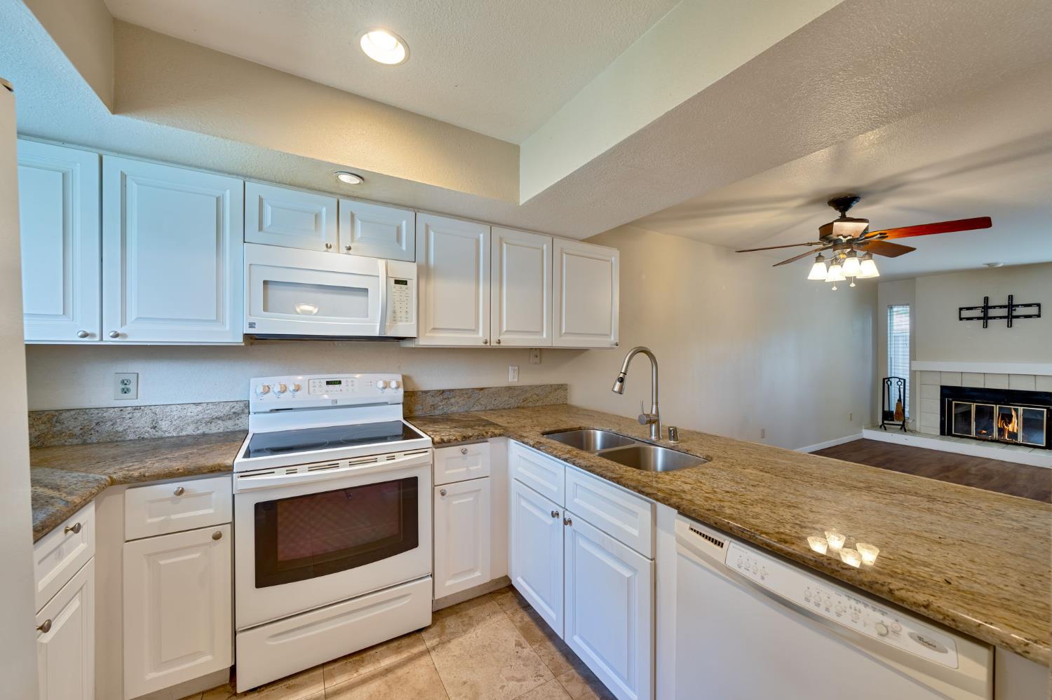 9237 Madison Avenue Orangevale, CA 95662 - Photo 13 of 40 a kitchen with kitchen island granite countertop a sink stainless steel appliances and white cabinets
