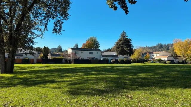 a view of a big house with a big yard and large trees