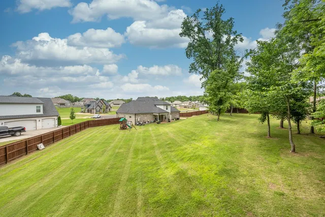 a view of a green yard with a house and large trees