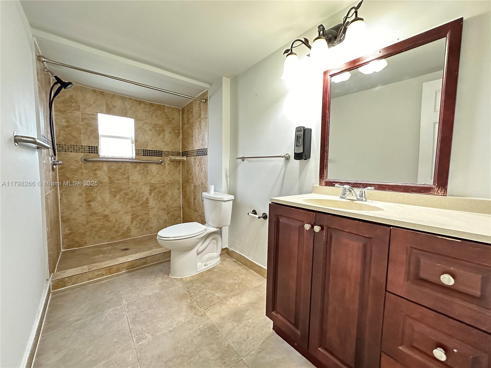 2811 Northwest 88th Street, Unit 1 Miami, FL 33147 - Photo 7 of 10 a bathroom with a toilet a sink and a mirror