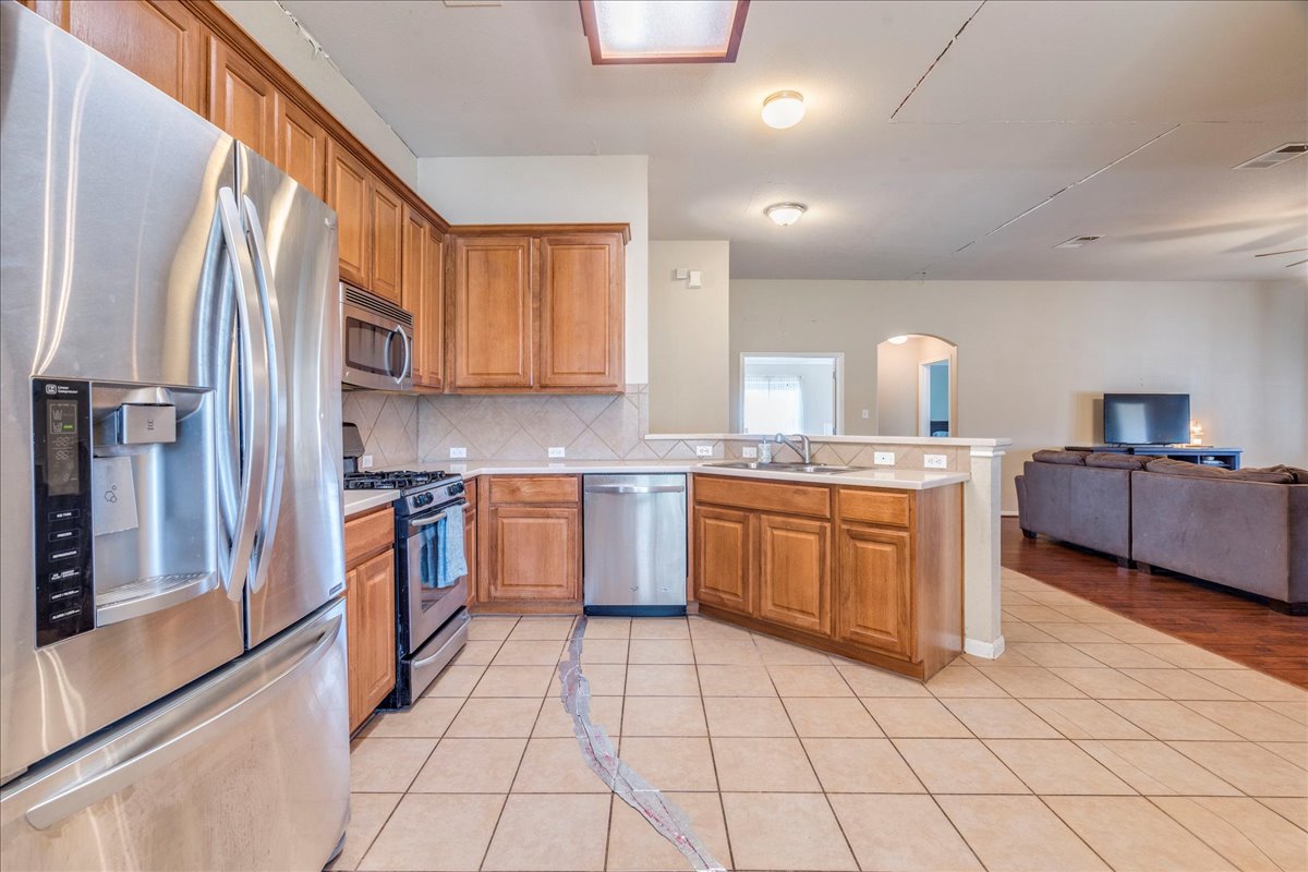 18424 Dry Brook Loop Pflugerville, TX 78660 - Photo 25 of 25 Kitchen featuring stainless steel appliances, open floor plan, light tile patterned floors, wood finish cabinetry, and arched walkways