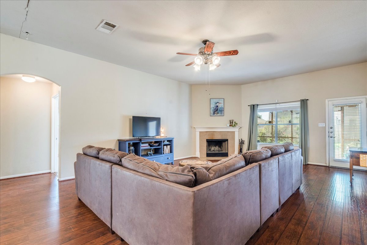 18424 Dry Brook Loop Pflugerville, TX 78660 - Photo 12 of 25 Living room with arched walkways, dark wood finished floors, a ceiling fan, and a fireplace