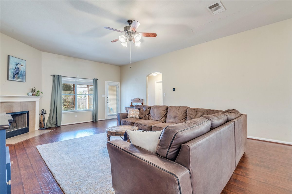 18424 Dry Brook Loop Pflugerville, TX 78660 - Photo 13 of 25 Living room with arched walkways, a ceiling fan, a fireplace, and dark wood finished floors