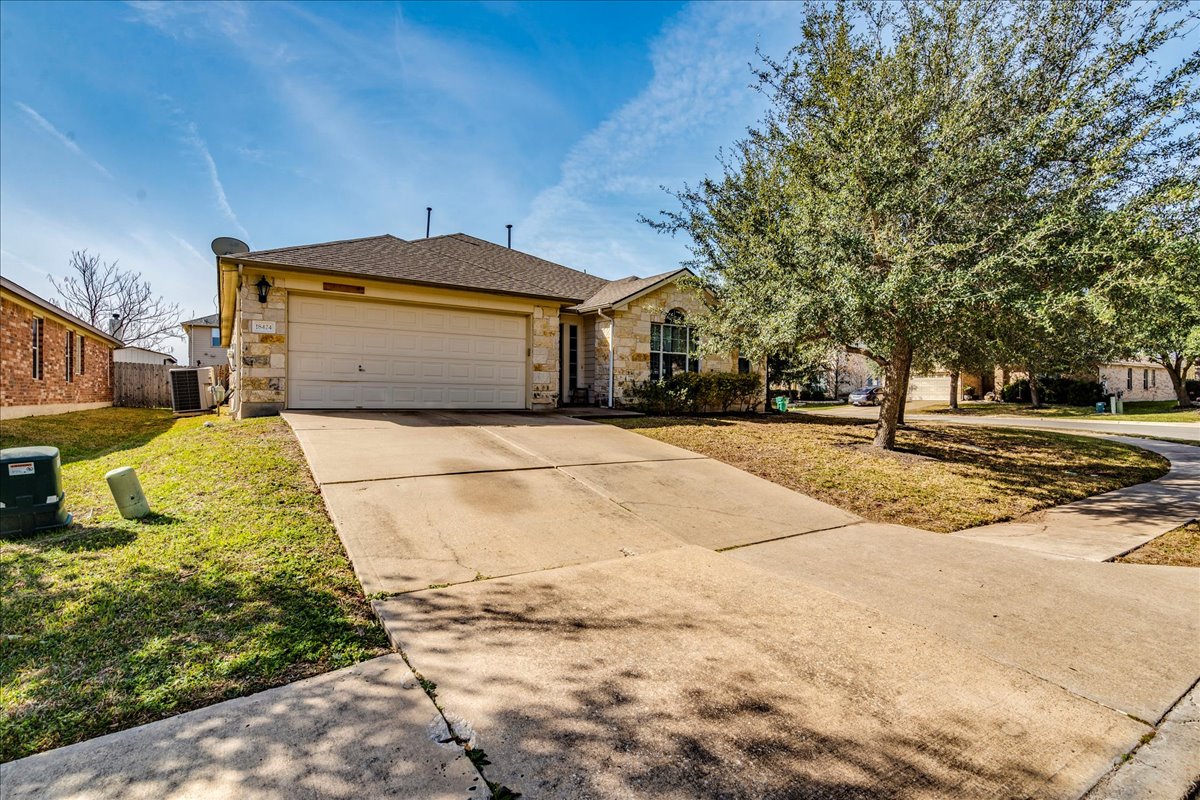 18424 Dry Brook Loop Pflugerville, TX 78660 - Photo 5 of 25 View of front of property featuring stone siding, driveway, a garage, a front lawn, and a shingled roof