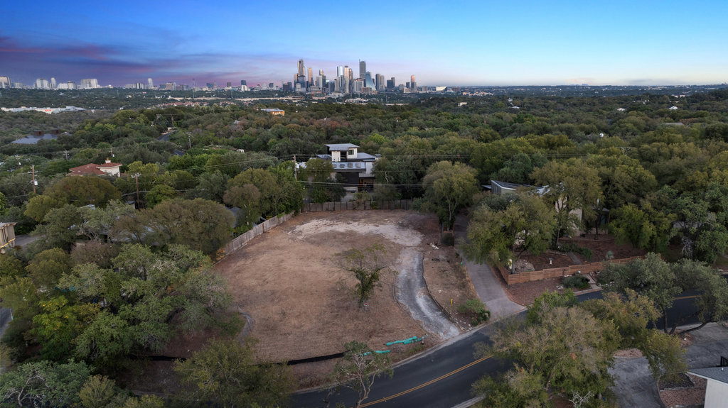 303 Ridgewood Road Austin, TX 78746 - Photo 4 of 40 Incredible twilight aerial showcasing a spacious buildable lot framed by mature trees with breathtaking views of the Austin skyline. A rare opportunity to design a custom home in a premier hillside location just minutes from downtown.