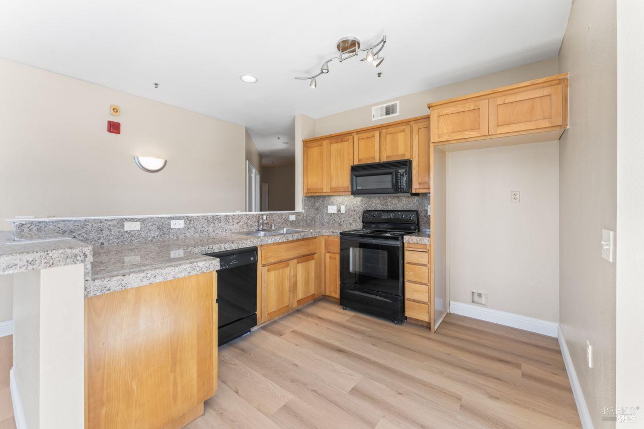 655 12th Street, Unit 311 Oakland, CA 94607 - Photo 8 of 29 a kitchen with granite countertop a refrigerator stove top oven and sink