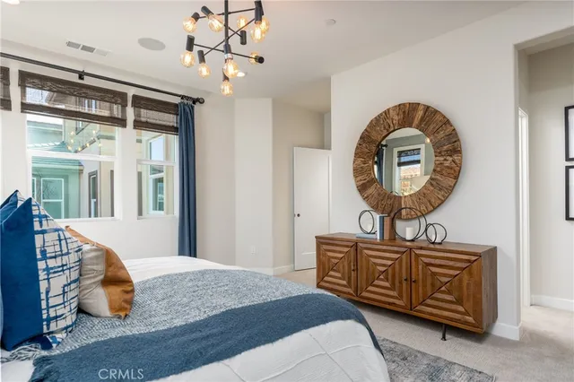 a bedroom with a bed a mirror and a chandelier