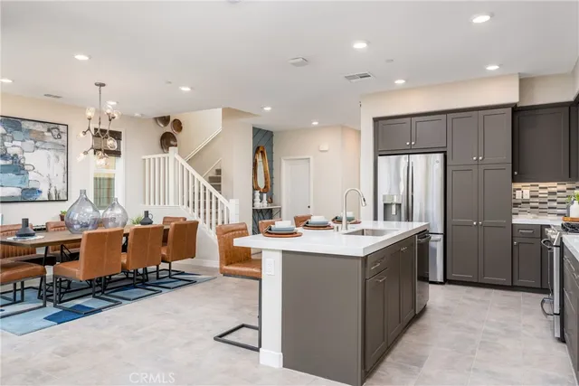 a room with stainless steel appliances kitchen island granite countertop a refrigerator and a sink