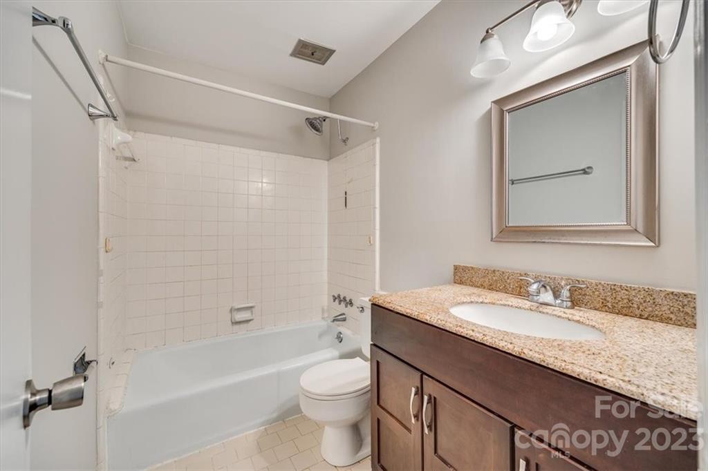 3722 Park Road, Unit I Charlotte, NC 28209 - Photo 20 of 27 a bathroom with a granite countertop sink a toilet a mirror a bathtub and shower