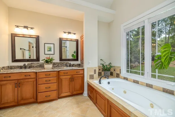 a bathroom with a granite countertop tub a double vanity sink a large mirror and a bathtub
