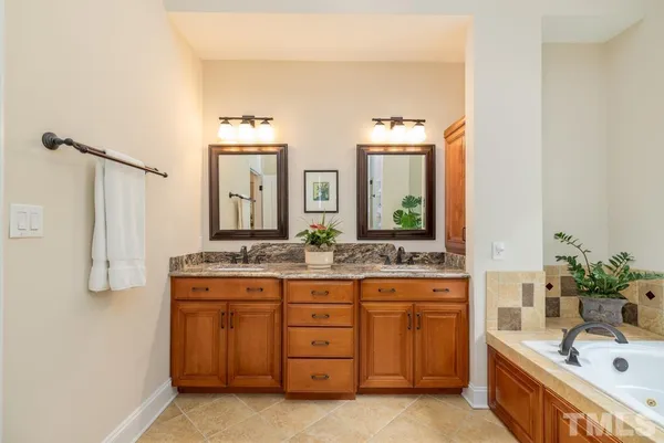 a bathroom with a granite countertop double vanity sink a mirror and a bathtub